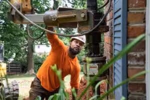 A foundation repair specialist installing a helical pier on a home