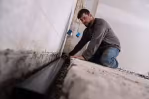 Man installing basement drainage channel pipe